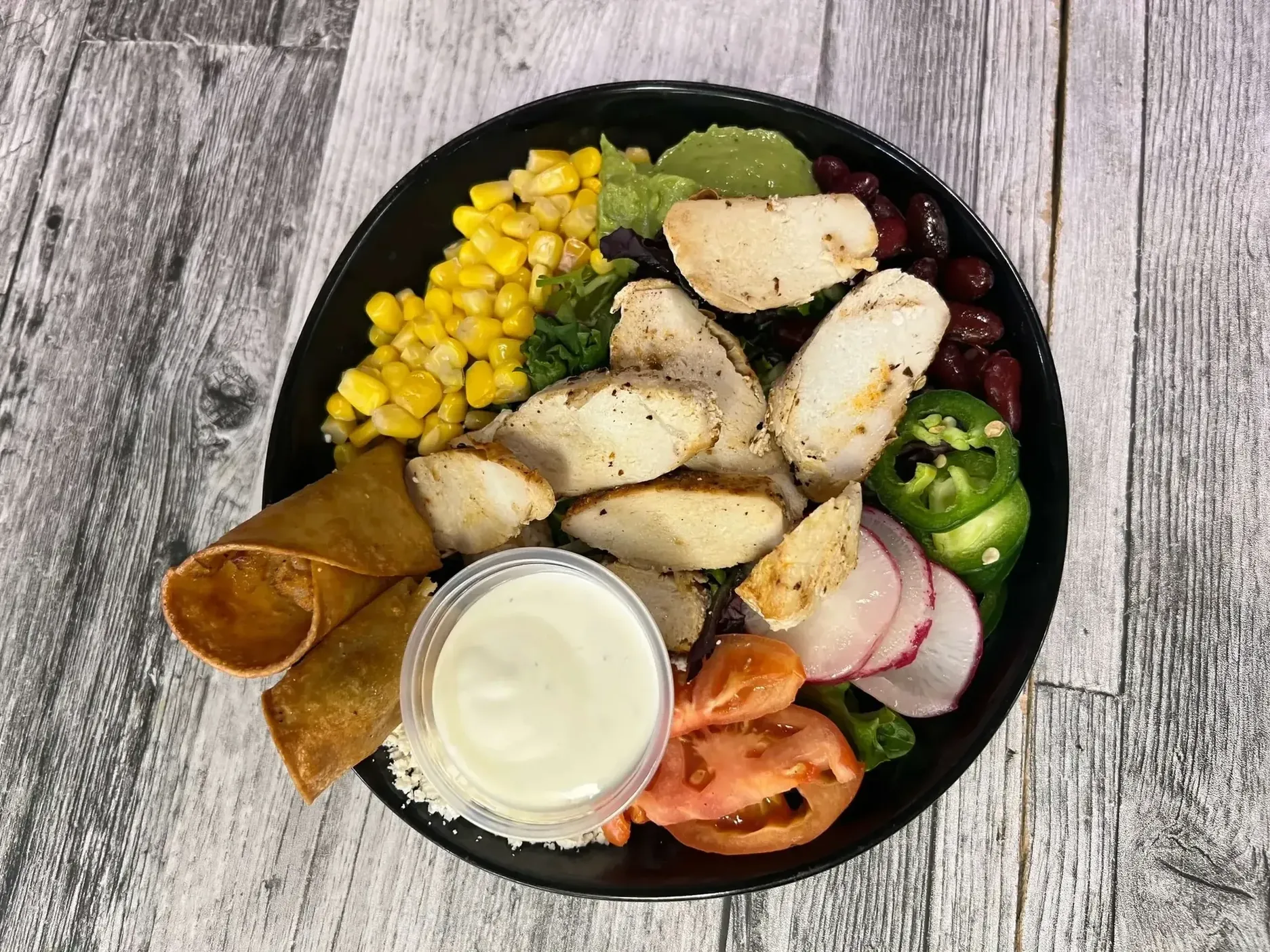 Signature chicken bowl with corn, beans, greens and fresh vegetables at Maison Croissant & Bowls, St. Vital Winnipeg